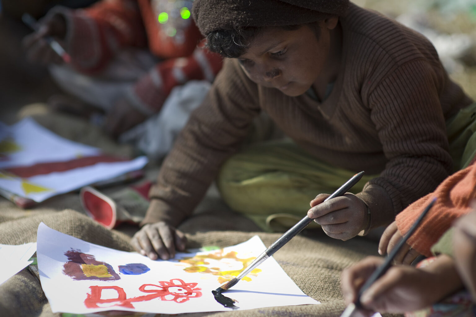 A child at an Aasraa session, head down, painting with a brush